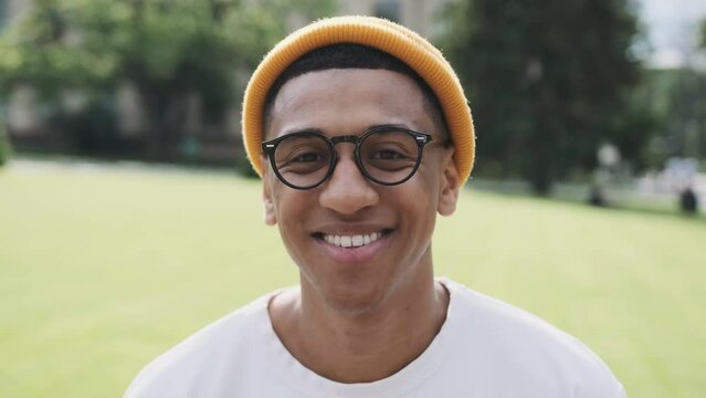 Portrait of a young stylish African American student. Young cheerful mulat wearing glasses smiling at the camera.