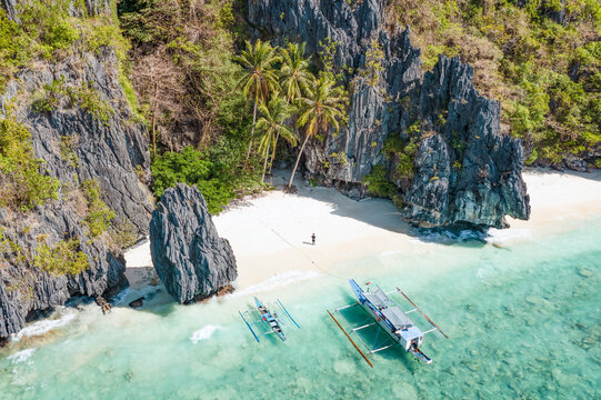 View from above, stunning aerial view of a person on the Entalula Beach, a white sand beach bathed by a crystal clear water. Entalula island, Bacuit Bay, El Nido, Palawan, Philippines.