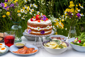 Scandinavian midsummer meal with strawberry and cream cake, potato salad, salmon and eggs