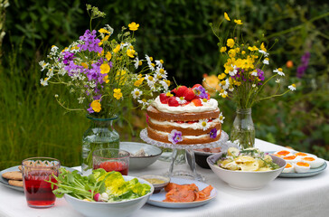 Scandinavian midsummer meal with strawberry and cream cake, potato salad, salmon and eggs