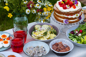 Scandinavian midsummer meal with strawberry and cream cake, potato salad, salmon and eggs