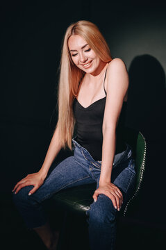 The girl is sitting on a chair, studio shot gobo mask. Long-haired girl with blond hair.