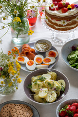 Scandinavian midsummer meal with strawberry and cream cake, potato salad, salmon and eggs