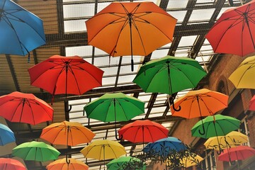 Bunte Regenschirme unter Glasdach von hohem Bahnhofsgebäude 