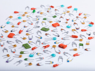 Capacitors. Different type in different colors. Colorful small ceramic, metal, film capacitors. Green, blue, orange, red capacitors. On white background. Perspective view close-up.