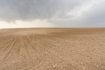 Fototapeta na wymiar Landscape of a plowed cereal field at planting time with a stormy sky. Agricultural insurance concept