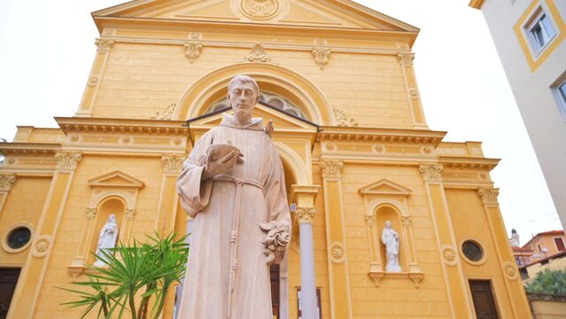 Square with statue of a priest and a church on the background in Sanremo, Italy
