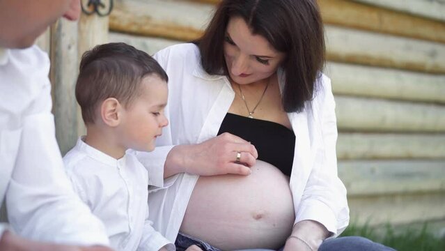 Pregnant woman with husband and son. A young family is waiting for the birth of their second child. Wife with husband and child relaxing in nature in a city park.