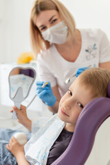 Cute little boy sitting on dental chair and having dental treatment