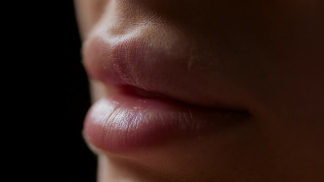 Macro shot of lips of white-skinned female model moving on black background | Lip texture shot for lip care cosmetics commercial