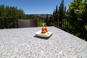 A crispy white blood sausage tapa punctured with a cherry tomato. Served on the terrace of the...
