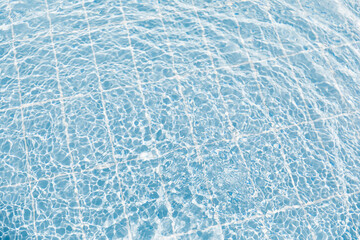 Clear water surface with ripple wave splashes and drops in swimming pool. Abstract turquoise or blue texture water wave and sunlight shadow reflections for background.