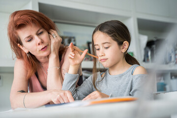Friendly mother helping to her daughter to do homework