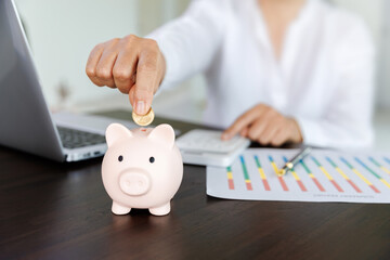 A pig piggy bank on the table and woman picking up a coin for save money, saving money or savings...