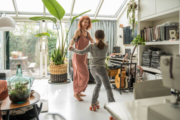 Mother and her little daughter in roller skates dancing at the living room