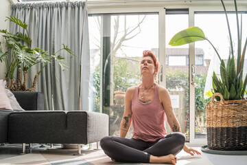 Woman wearing domestic clothes soothing her breath while doing yoga exercises