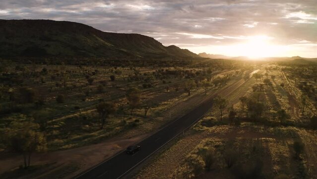 Car Driving Down Desert Highway At Sunset