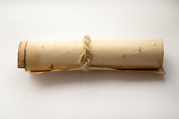 Ancient rolled up parchment paper scroll, insulated on a white background, tied with string.
