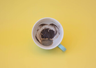 Blue cup with coffee grounds on a yellow background