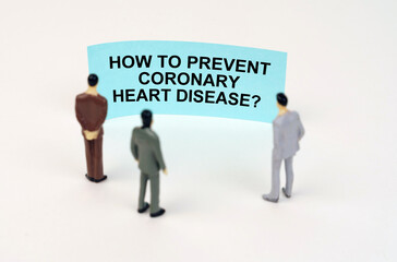 Miniature figures of people stand in front of a blue sign with the inscription - How to Prevent Coronary Heart Disease