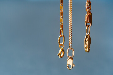 Gold clasps of a golden chains hanging in the air. Soft focus. Copy space.