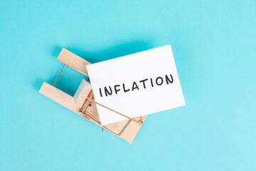 Paper with the word inflation in a mousetrap, high financial burden, increased costs and expenses...