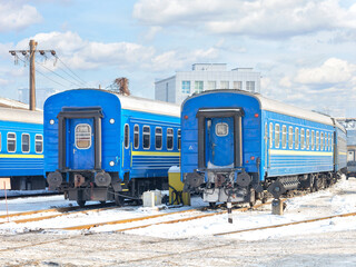 Blue train cars against the background of the winter parking of the railway depot.