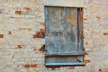 Old brick wall with wooden shuttered window.