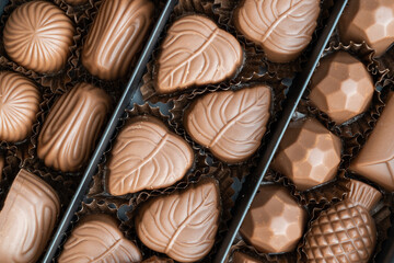 A box of chocolates of various shapes and flavors. The concept of a first date and confectionery sweets. Chocolates in box top view.
