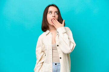 Young Ukrainian woman isolated on blue background yawning and covering wide open mouth with hand