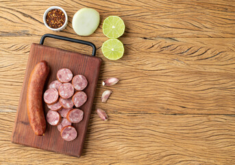 Fototapeta na wymiar Calabrese pork sausage with slices over wooden board with seasonings and copy space