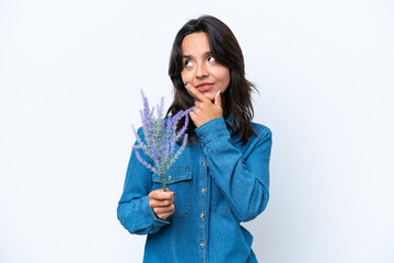 Young hispanic woman holding lavender isolated on white background having doubts