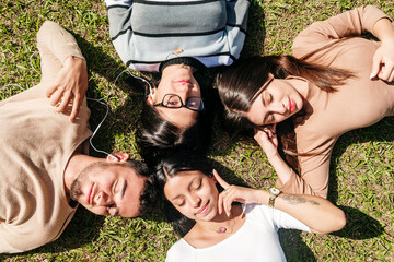 Group of friends lying on the grass while listening to music on a sunny day