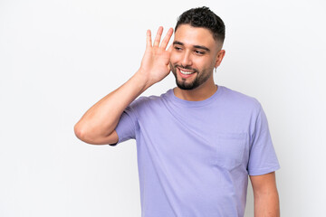 Fototapeta premium Young Arab handsome man isolated on white background listening to something by putting hand on the ear