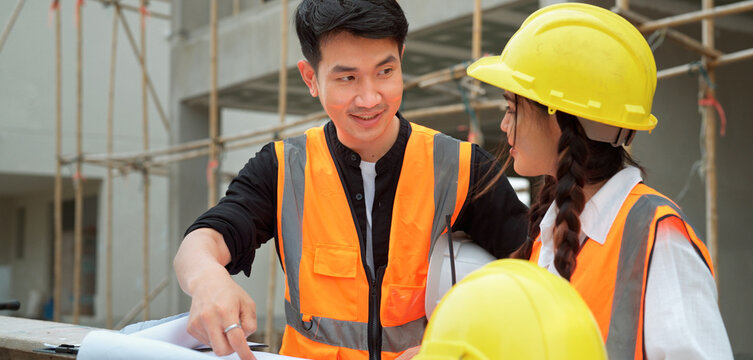 Smart male civil engineer foreman with safety vast assigning work to female construction worker checking and surveying construction building working together with engineer team