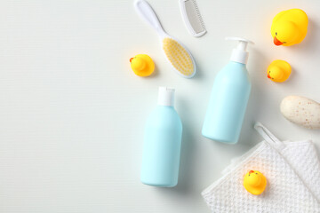 Kids bath accessories. Baby bathing concept. Shampoo and shower gel bottles with yellow ducks and towel on white table. Flat lay, top view.