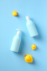 Baby shower gel and shampoo bottles with yellow rubber ducks on blue background