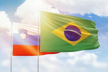 Sunny blue sky and flags of brazil and slovenia