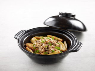 Stewed Eggplant with Minced Pork and Salted Fish in Claypot isolated on wooden board side view on grey background