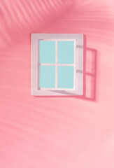 Window on a pastel pink wall with palm shadow and clear blue sky in the background. Summer vacation minimal concept.