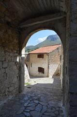 View of stone building and mountains through dark alleyway in Sperlonga, Italy - 509894607