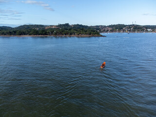 Small fishing boat in the middle of the river divided by the sea near the lighthouse
