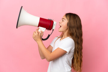 Child over isolated pink background shouting through a megaphone to announce something in lateral...
