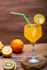 Orange fruit cocktail with a straw garnished with a slice of lemon in a large glass