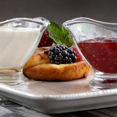 Cottage pancakes with berry jam, sour cream and berries.