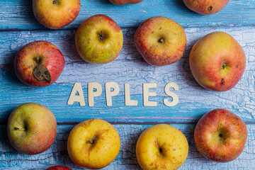 Yellow apples fruits background with apples word in wooden letters on a blue wooden background