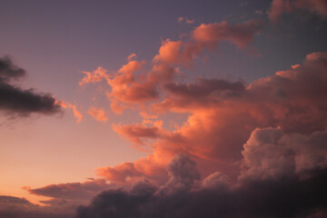 large cumulus cloud with shadowed base and top lit by golden twilight light, rising over the horizon.