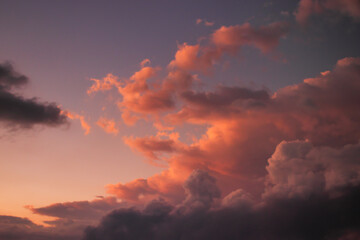 Fototapeta premium large cumulus cloud with shadowed base and top lit by golden twilight light, rising over the horizon.