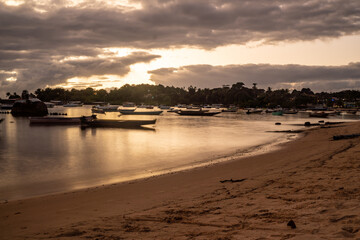 Fototapeta na wymiar Purple sunset on a river beach full of fishing boats in Itacaré