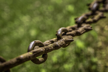 An old rusty chain hangs on a blurred background. Corrosion on metal.